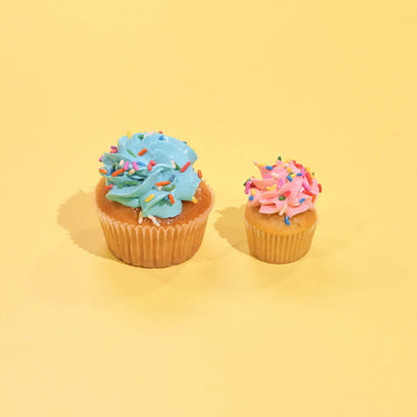 Vanilla Cupcakes with blue and pink buttercream icing and rainbow sprinkles on yellow background by Crumbs & Doilies